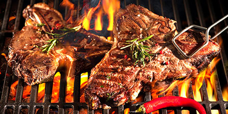 t-bones sizzling on a grill