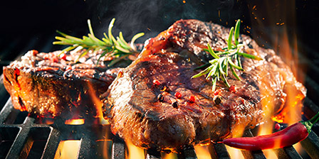 steaks sizzling on a grill